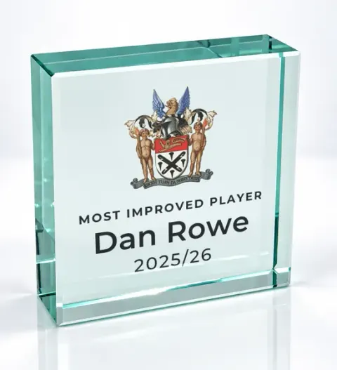 Small square glass award printed with a club crest and the wording Most Improved Player, Dan Rowe, 2025/26