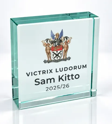 Small square glass award printed with a club crest and the wording Victrix Ludorum, Sam Kitto, 2025/26