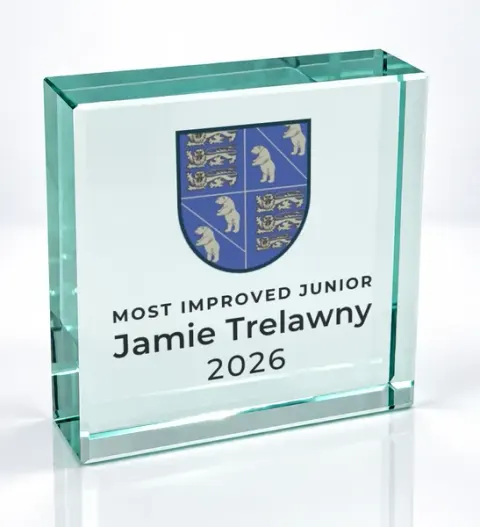 Small square glass award printed with a club crest and the wording Most Improved Junior, Jamie Trelawny, 2026