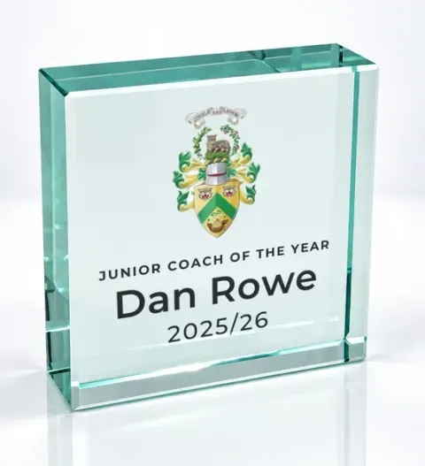 Small square glass award printed with a club crest and the wording Junior Coach Of The Year, Dan Rowe, 2025/26